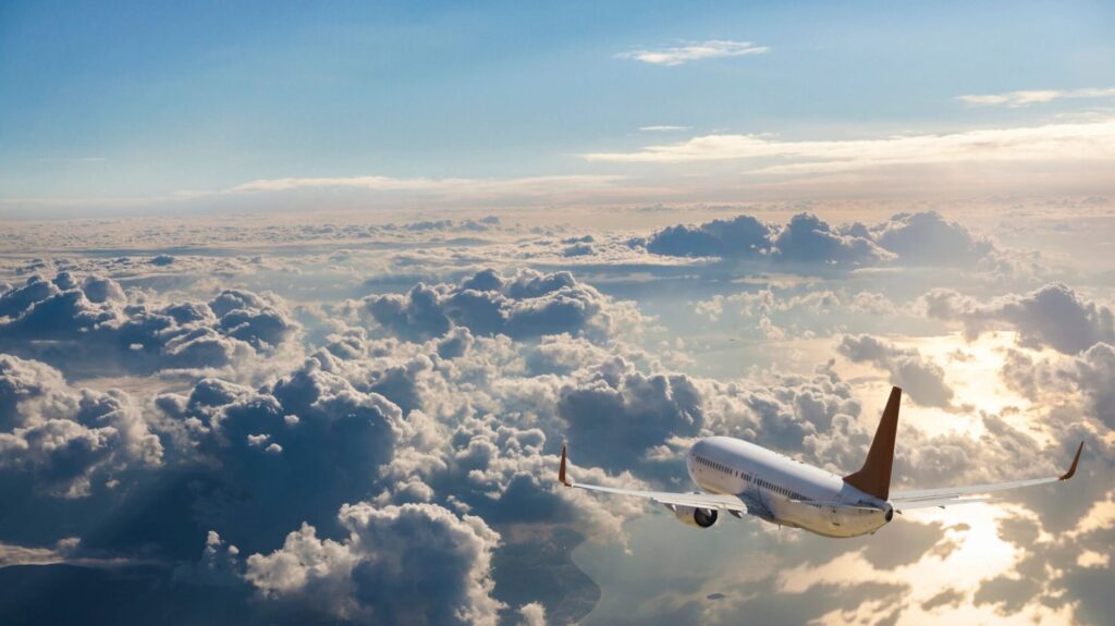 Passenger airplane flying above clouds at sunrise